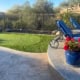Artificial turf putting green with golf hole and flag in backyard setting.